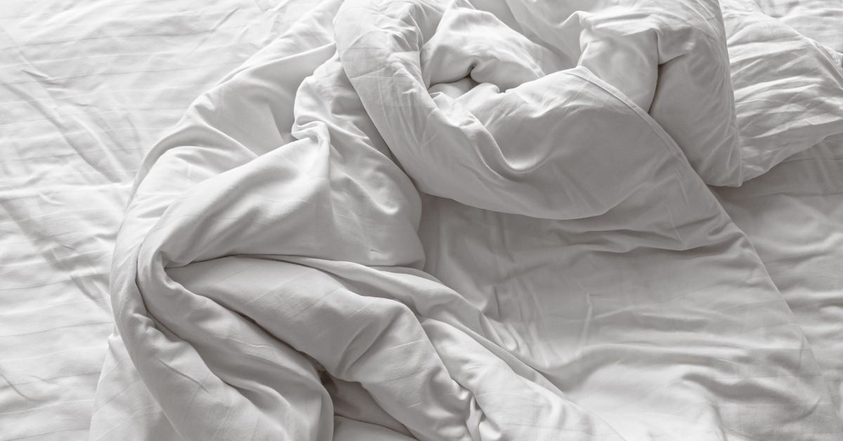 Starfish position guide — crumpled white bedding evoking comfort-first intimacy from Red Pleasures