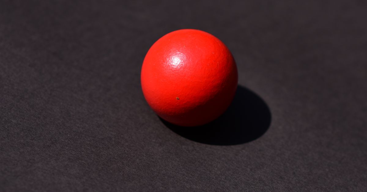 Ball gag guide - a single red ball on a dark background, education-first bondage guide from Red Pleasures, Ottawa, Canada