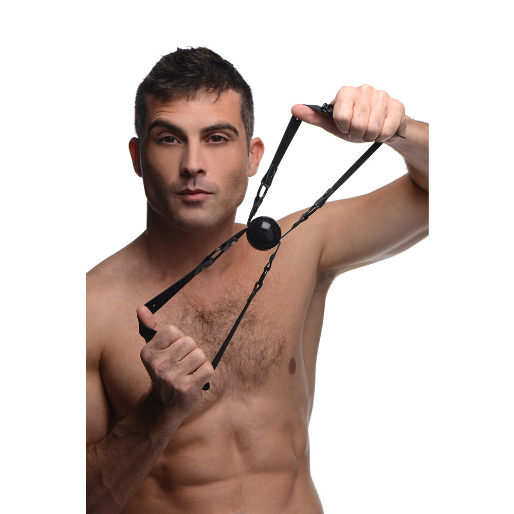 Man holding a black silicone gag with adjustable straps.