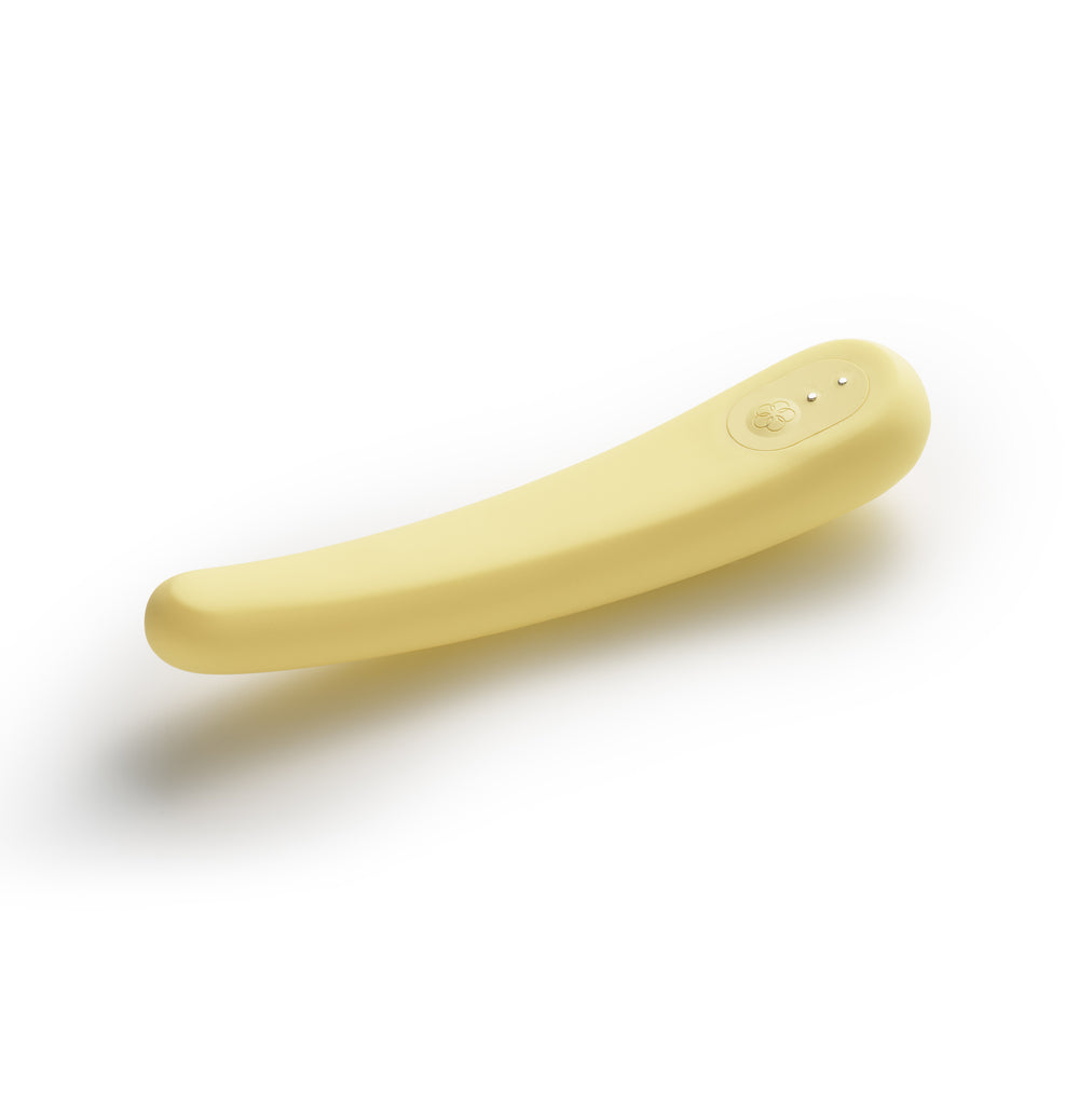 A pale yellow, curved silicone vibrator with a flower-shaped button.
