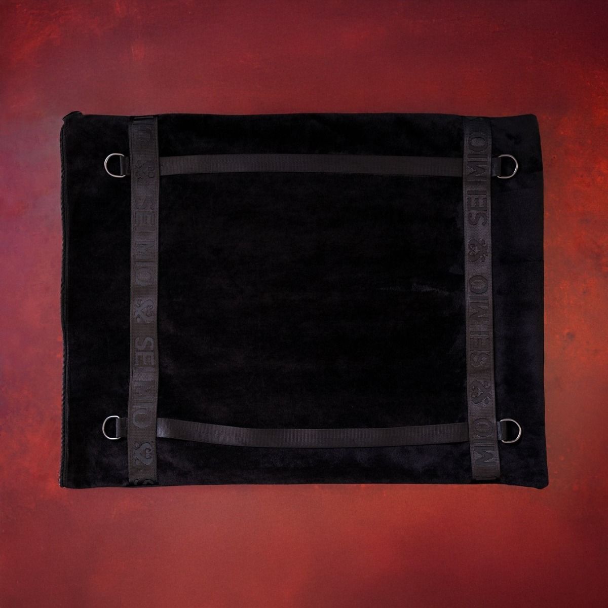 Black velvet positional support pillow with restraint loops.