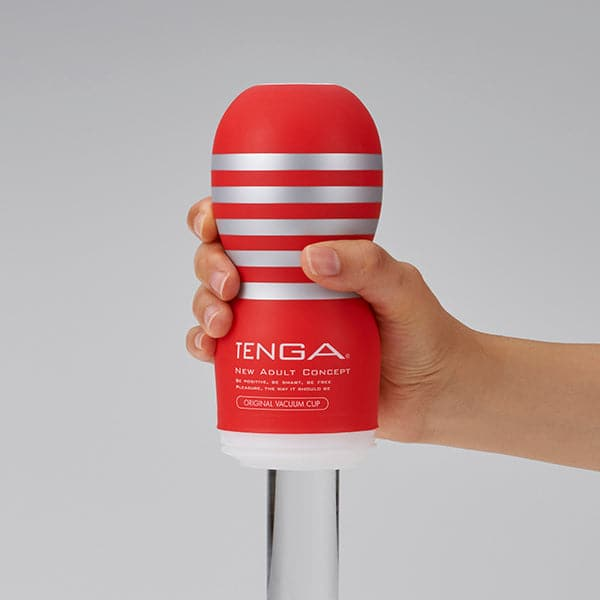 A red Tenga Original Vacuum Cup with silver stripes held in a hand.