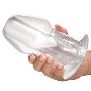 A clear hollow anal plug with a flared base is held in a hand.