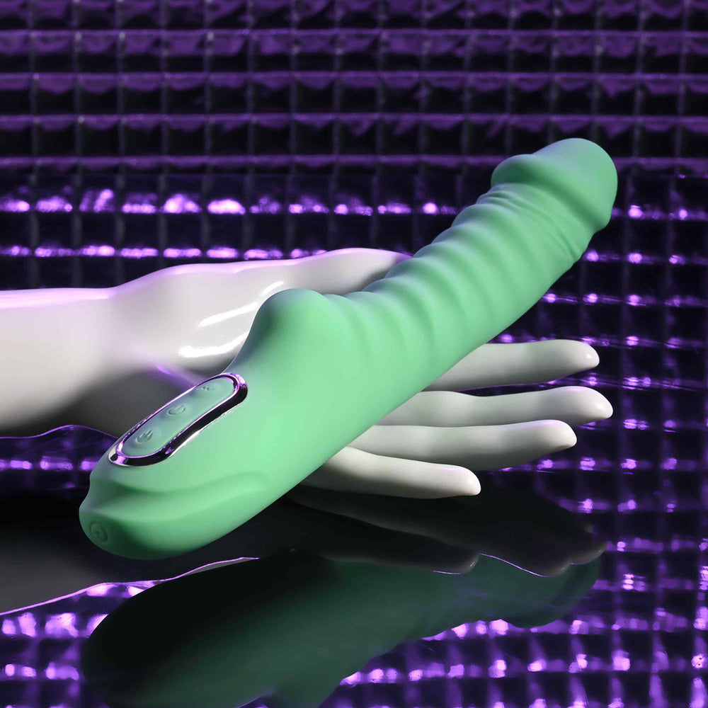 A green ribbed vibrator rests on a white hand against a purple textured background.