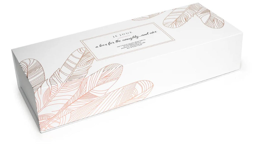 A white gift box with rose gold feather designs and text that reads "JE JOUE a box for the naughty...and nice".