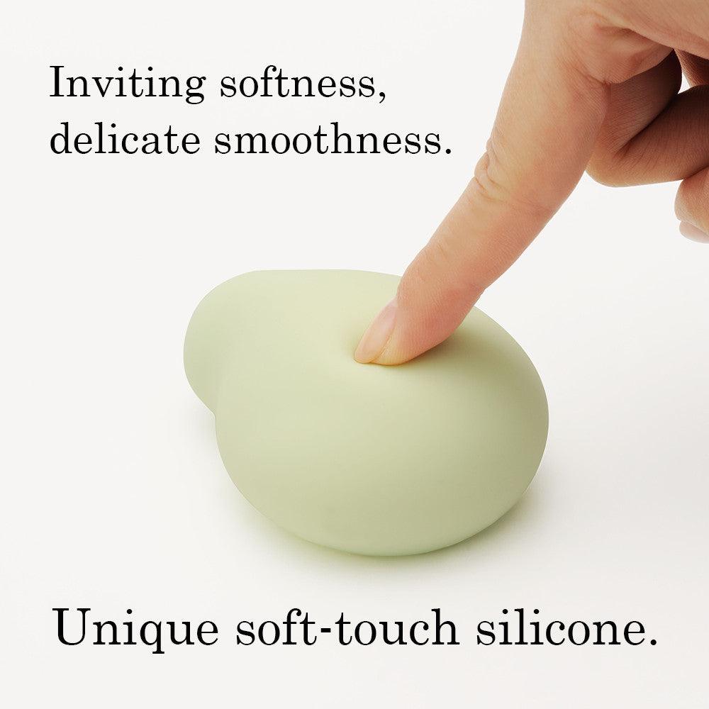 A finger presses into a soft, light green silicone object.