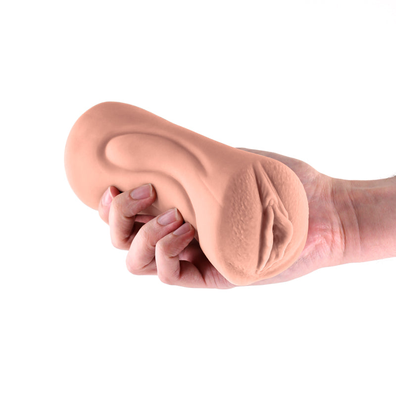 A tan, realistic TPE stroker with a textured shaft held in a hand.