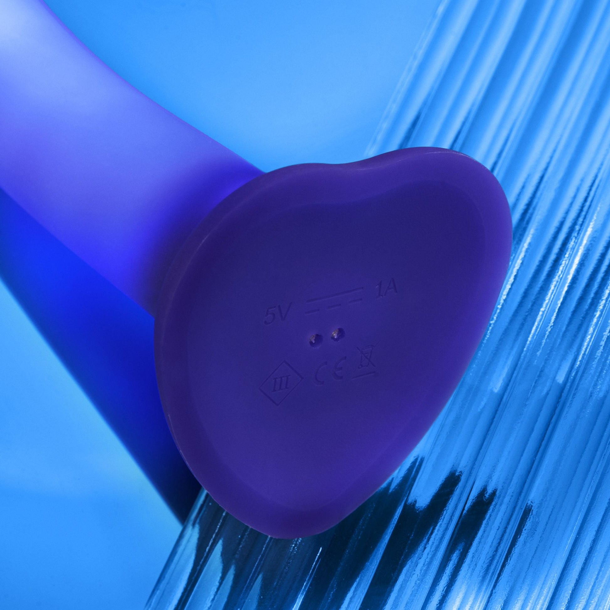 A purple heart-shaped silicone dildo with charging indicators and CE marking.