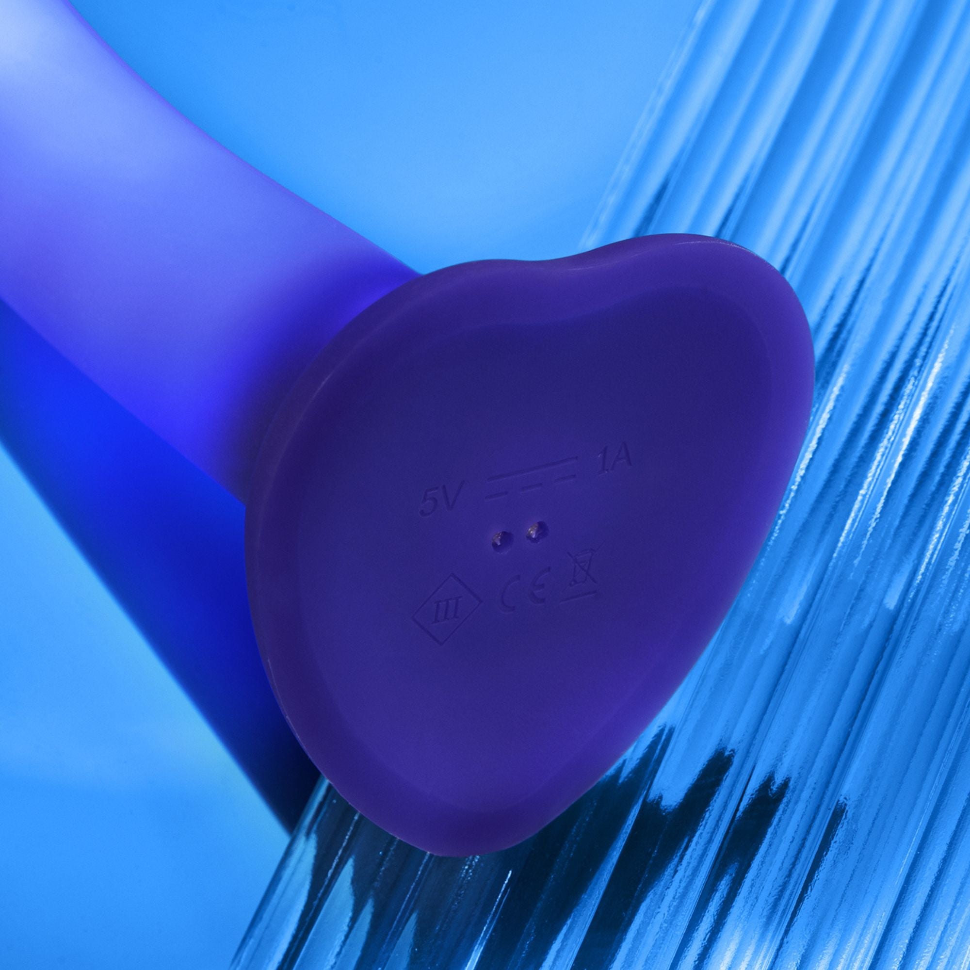 A purple heart-shaped silicone dildo with charging indicators and CE marking.