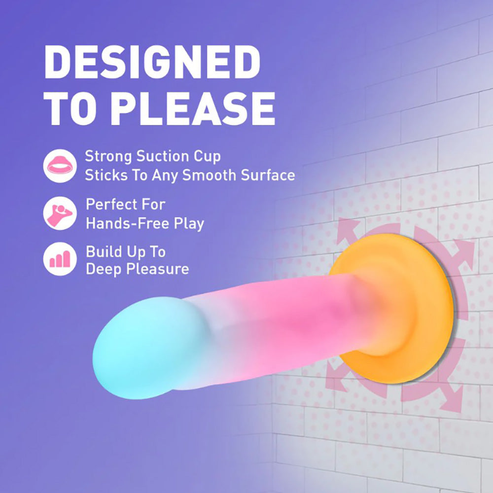 A pink and blue silicone stimulator with a yellow suction cup base attached to a tiled wall.