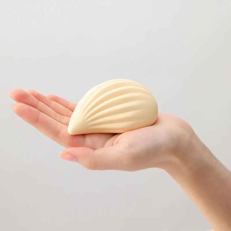A ribbed, shell-shaped silicone vibrator rests in a hand.