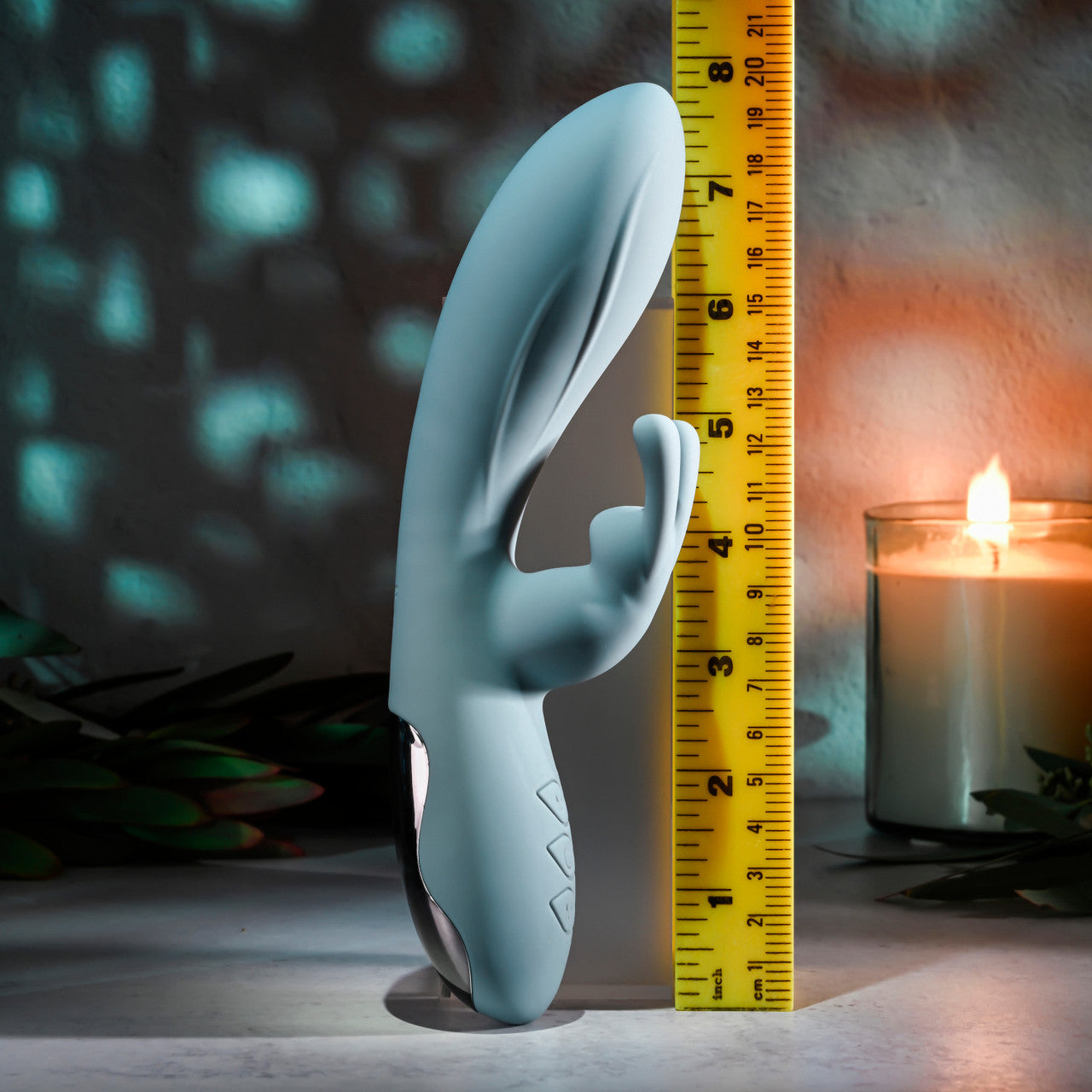 A light blue silicone rabbit vibrator with a ruler for scale.