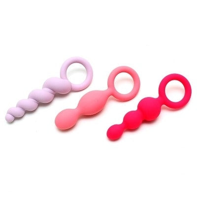 Three silicone anal training plugs in pink, purple, and red.