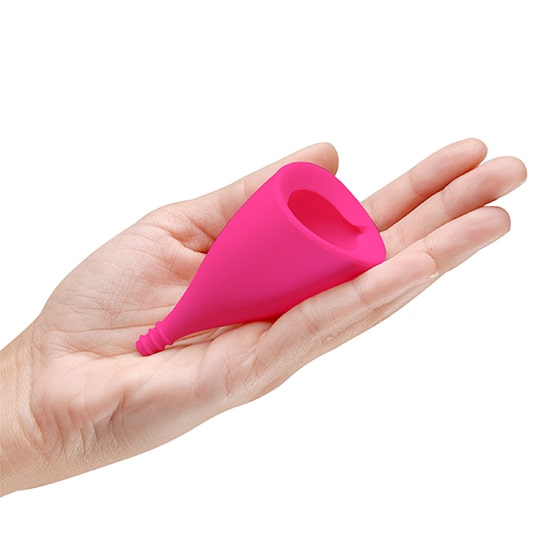 A pink Lily Cup menstrual cup is held in a hand.