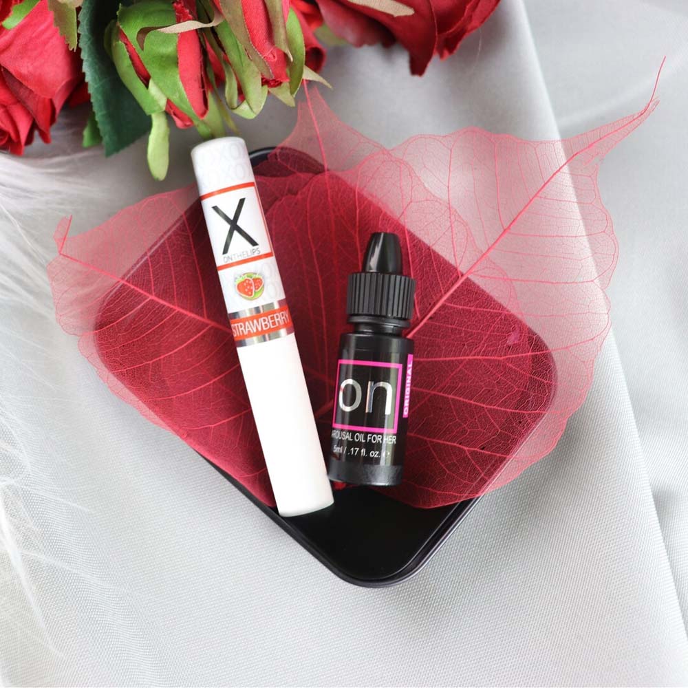 A strawberry flavored lip balm and arousal oil on a red leaf.