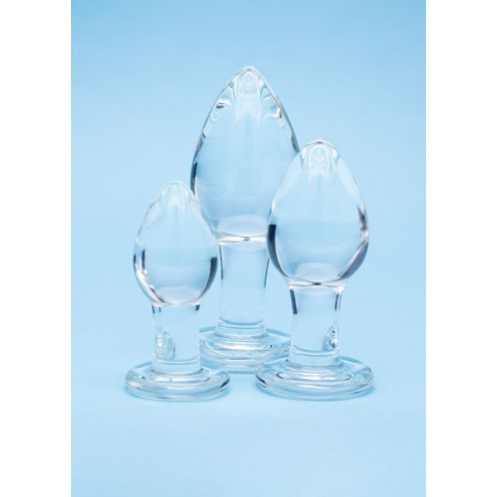 Three clear glass butt plugs of varying sizes on a blue background.