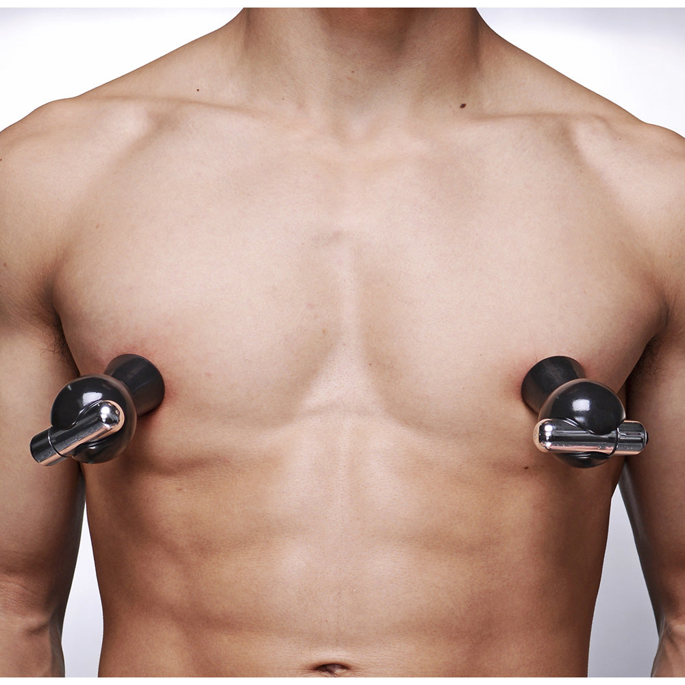 Black vibrating nipple suckers with silver accents on a person's chest.