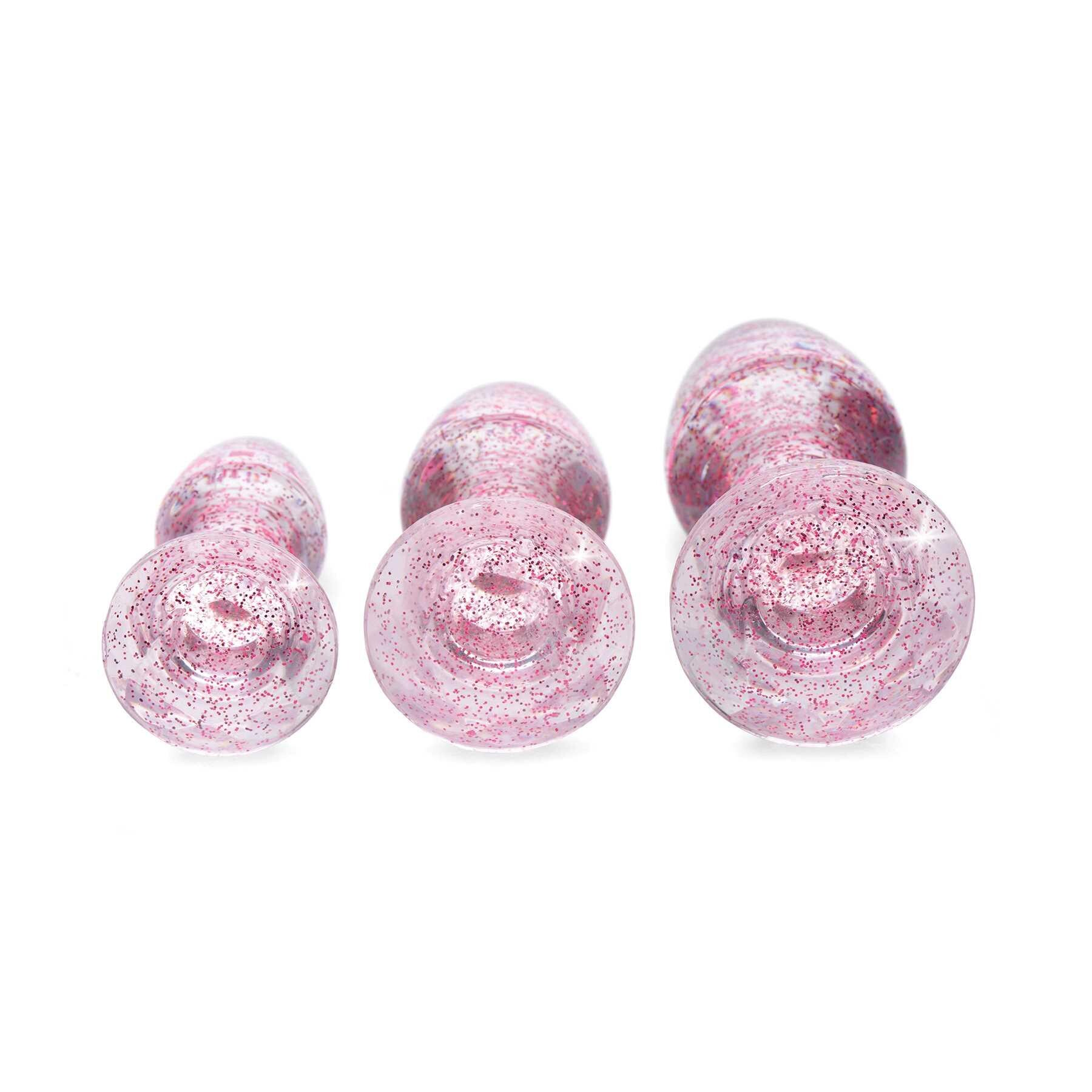 Three pink glitter acrylic anal plugs of varying sizes.