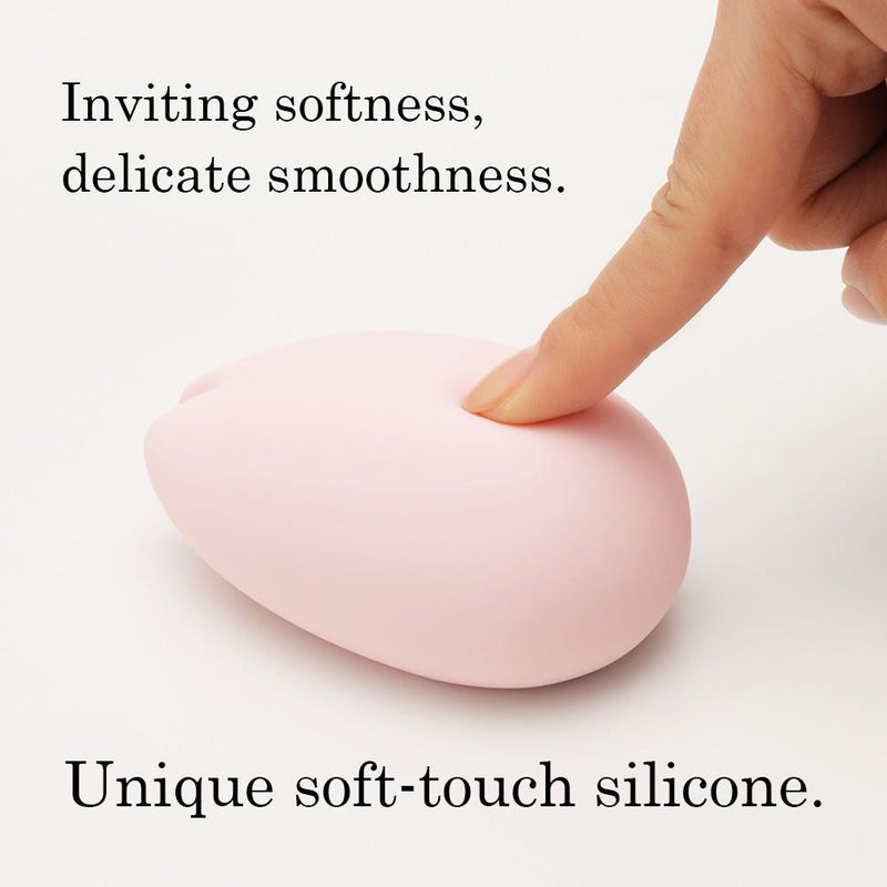 A pink silicone vibrator with a finger pressing into it.