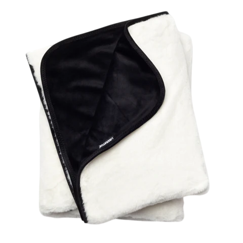 A white faux fur blanket with a black satin lining.