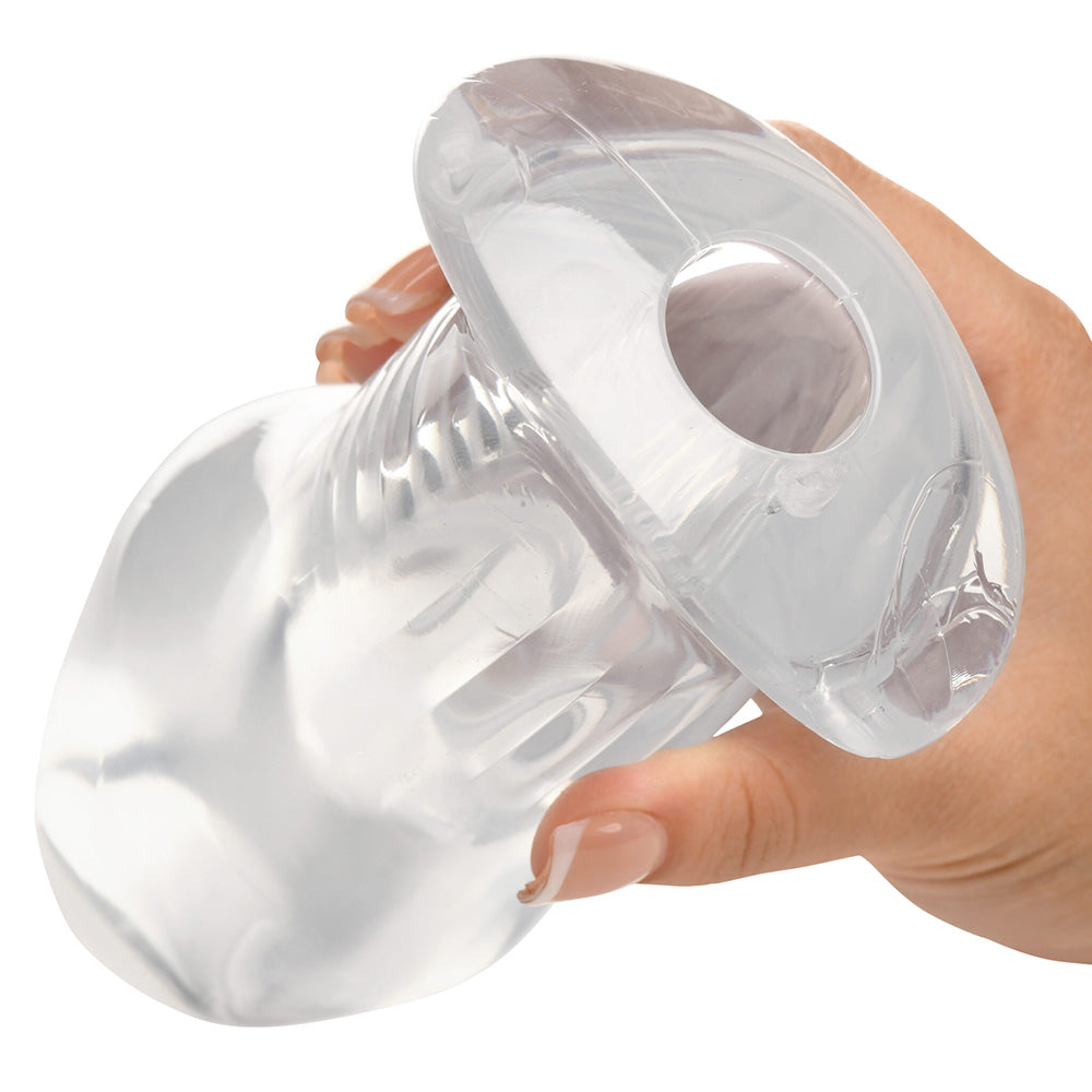 Clear hollow anal plug with flared base held by a hand.