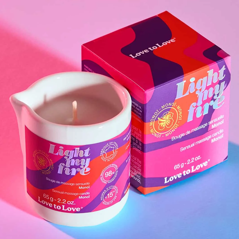 Monoi massage candle in a white ceramic pitcher with a pink and purple label.