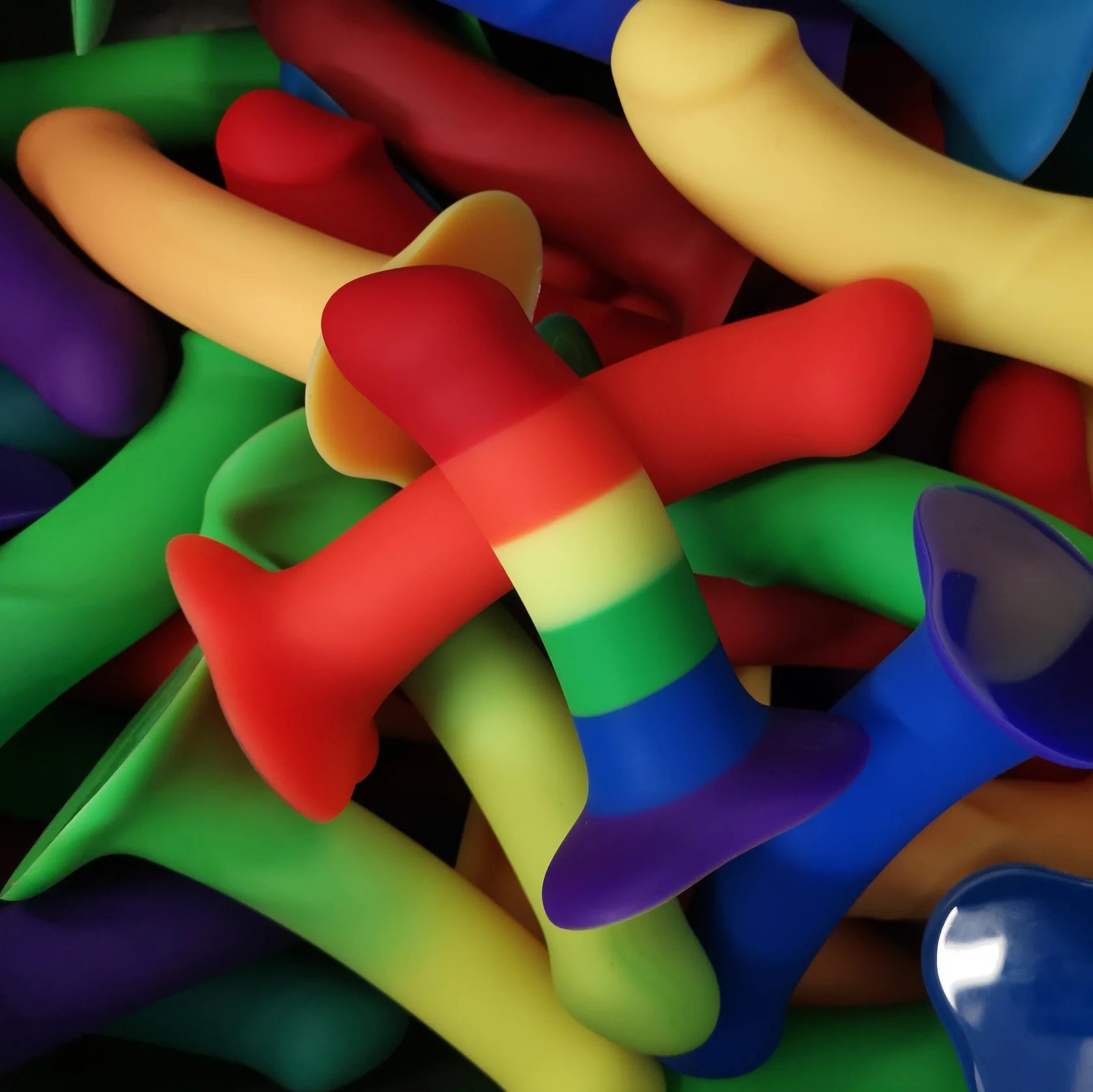 A pile of colorful dildos in various sizes and rainbow patterns.