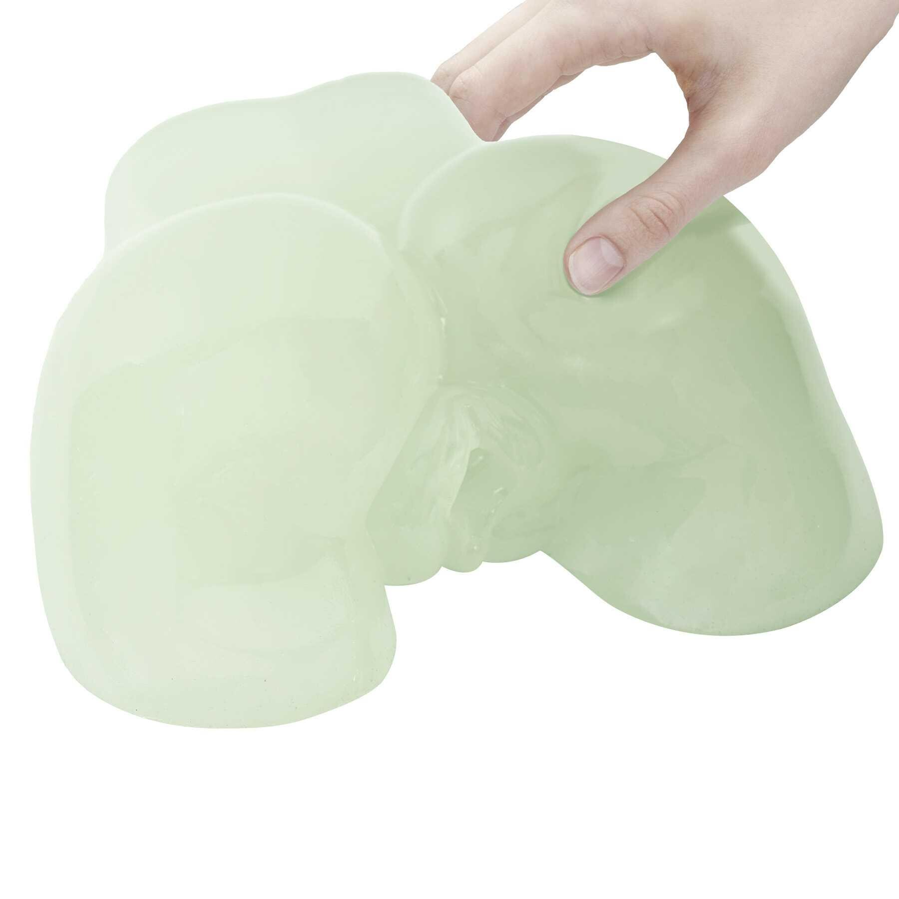 A hand squeezes a pale green, translucent, glow-in-the-dark male masturbator with dual entries.