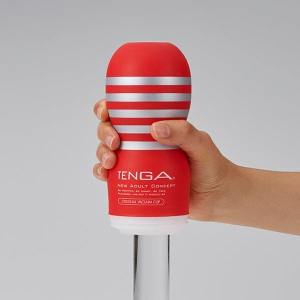 A red Tenga masturbator with silver stripes held in a hand.