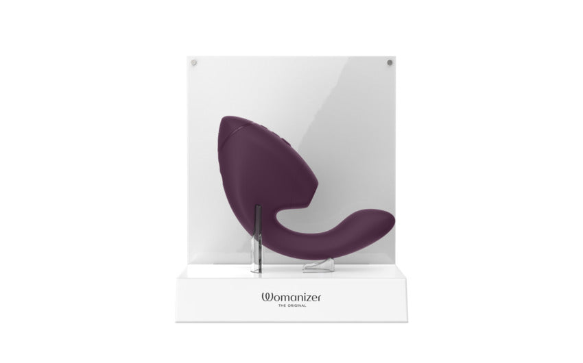 A purple Womanizer Next Duo dual stimulator on a white display stand.