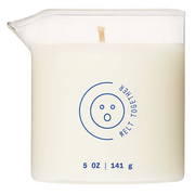 A white candle in a glass container with a pouring spout, featuring a blue circular logo and text.