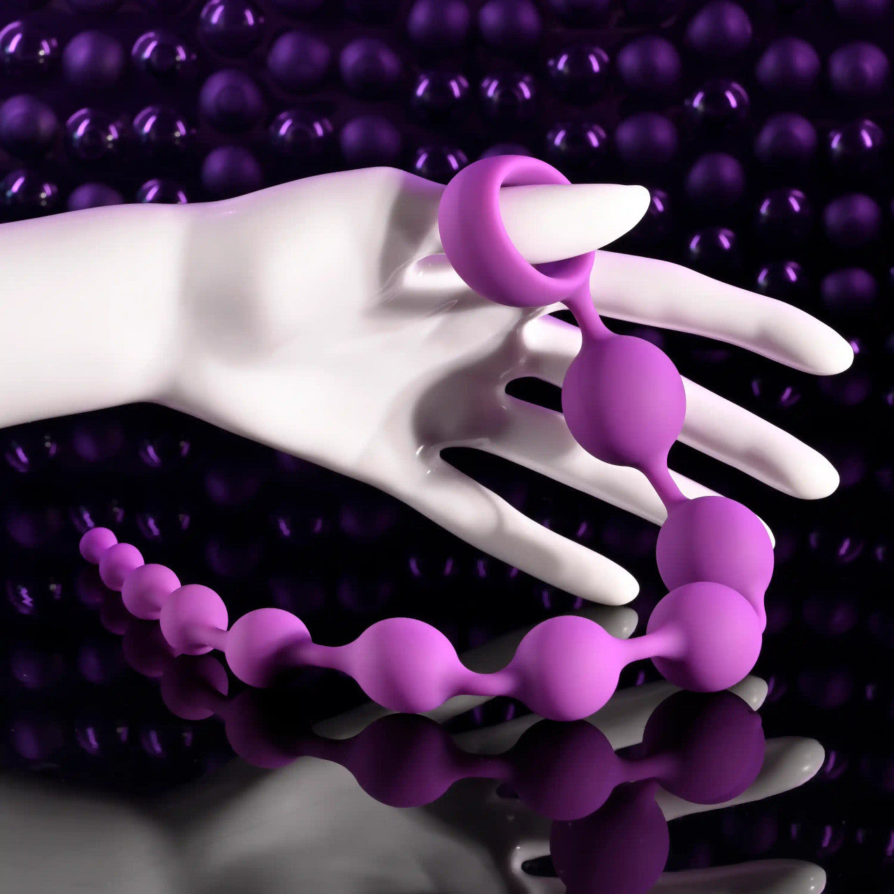 Purple beaded silicone anal string with a retrieval ring on a white mannequin hand.