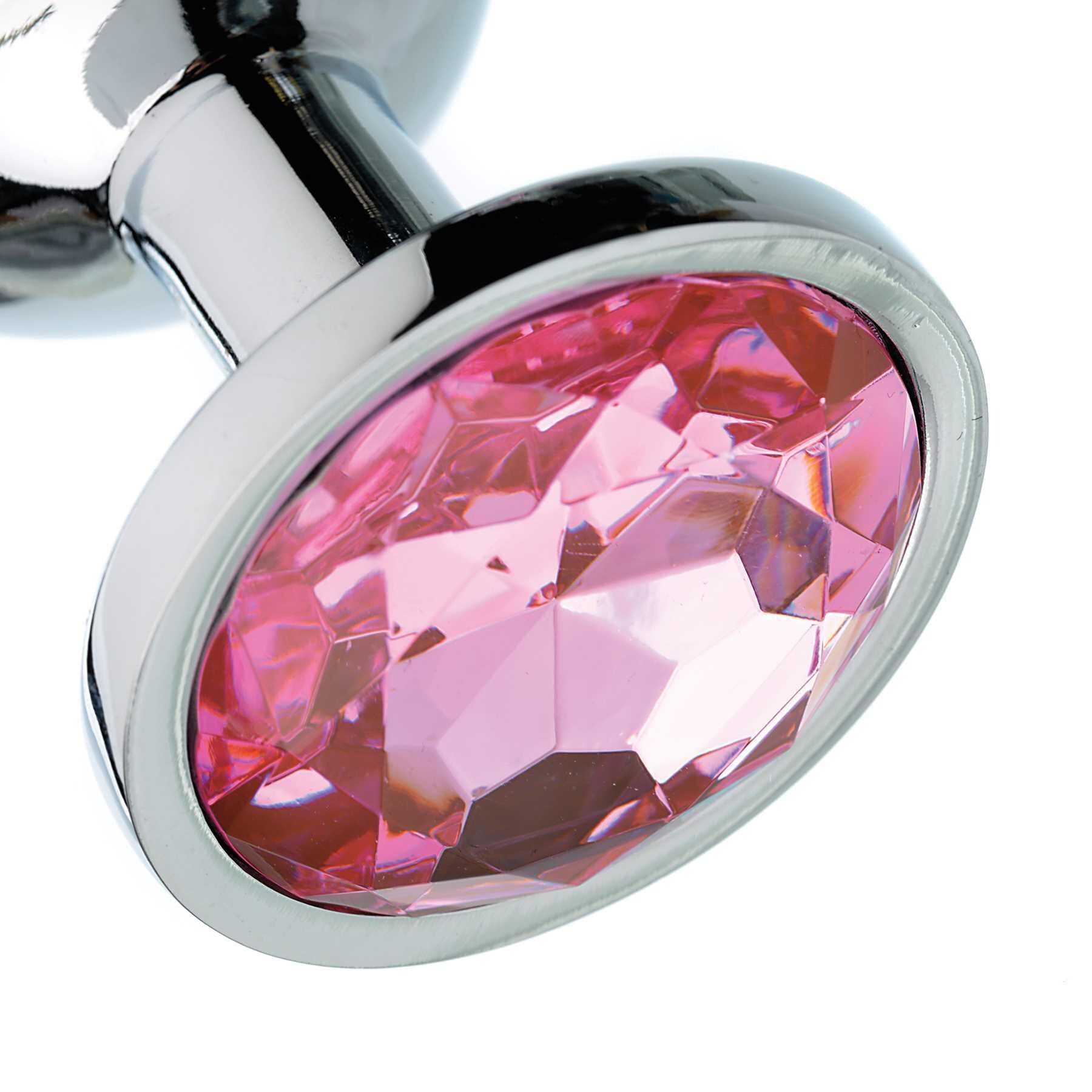 Close-up of a silver anal plug with a large faceted pink gem.