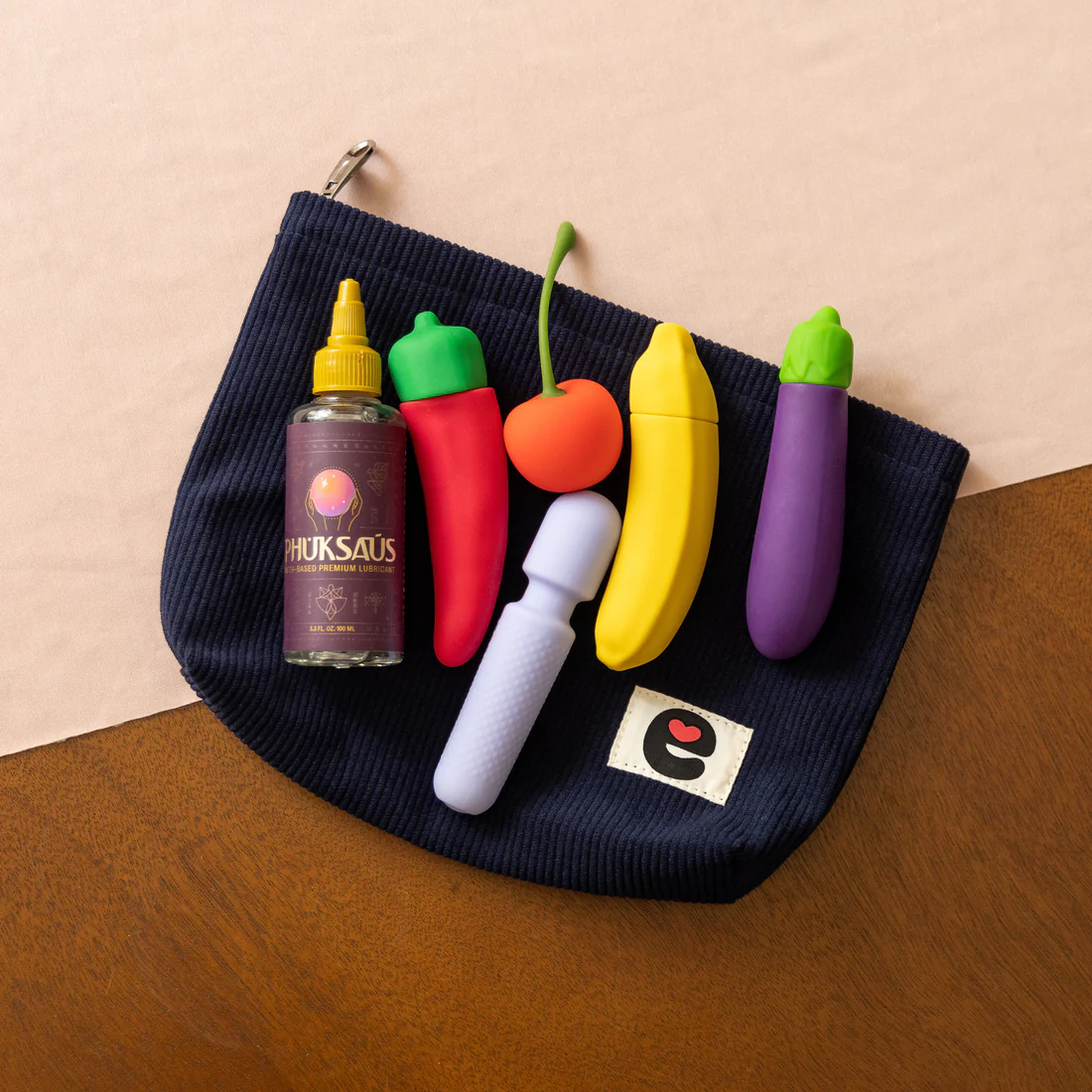 Midnight blue corduroy pouch with playful fruit-shaped items and a lubricant bottle.