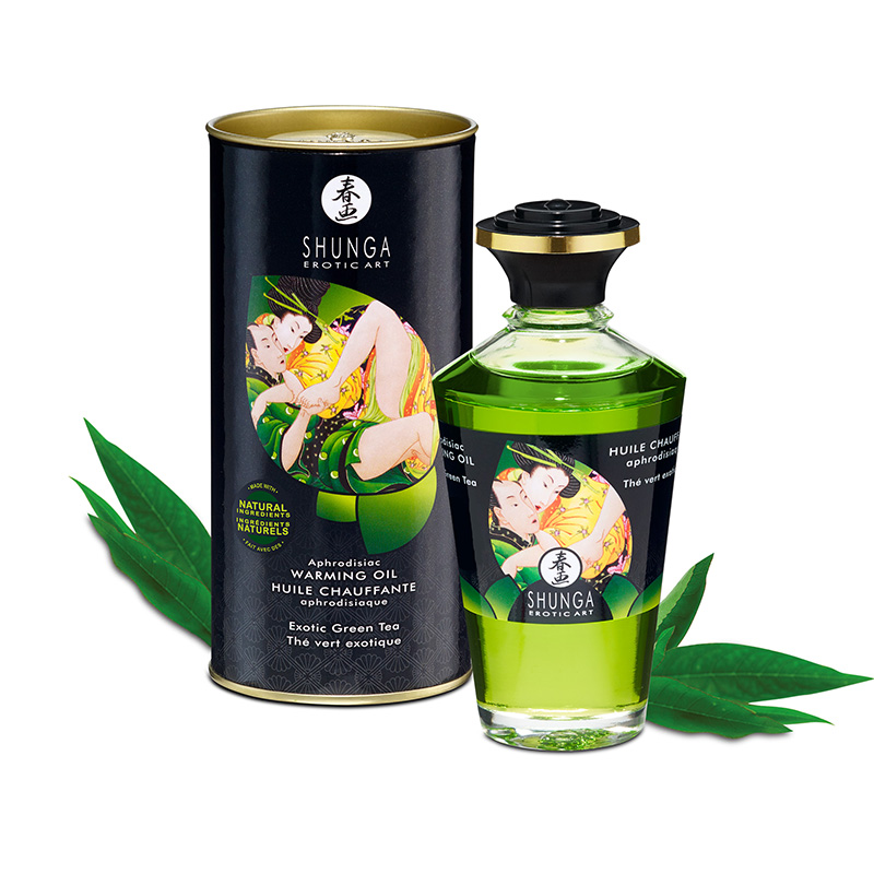 Shunga Exotic Green Tea warming massage oil in a green bottle next to its cylindrical packaging.