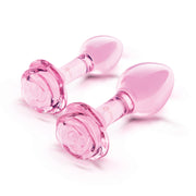 Two pink glass anal plugs with rose-shaped bases.