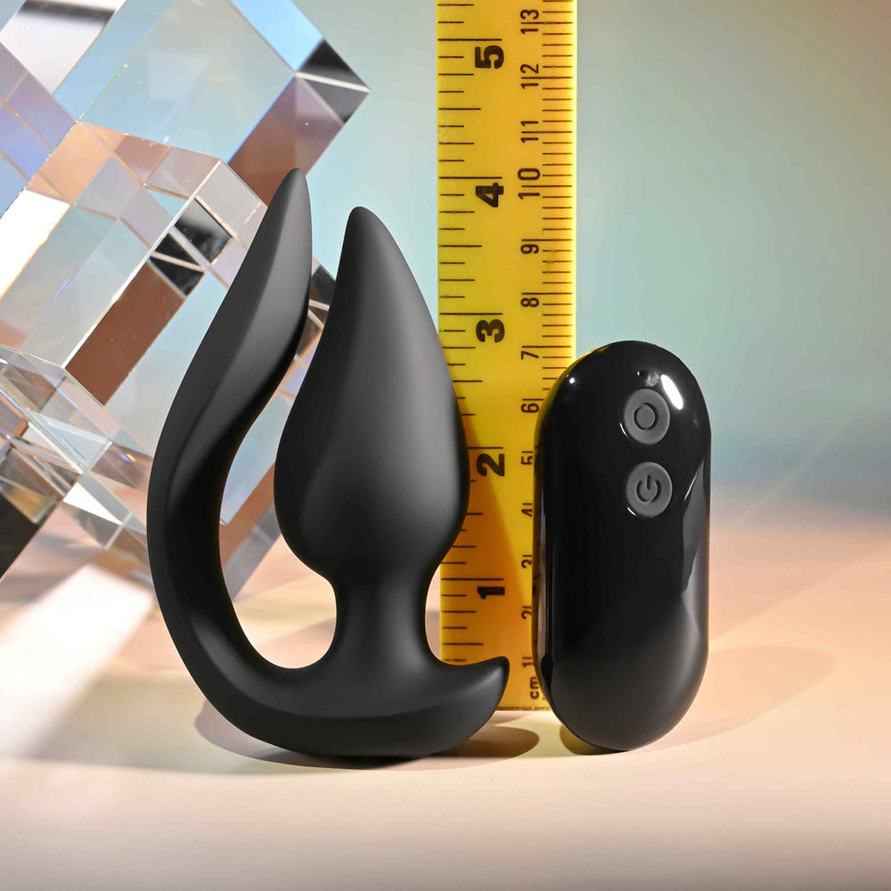 Black silicone plug with a curved handle and a remote control, measured against a ruler.