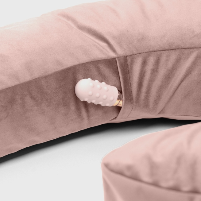 A pink velvet pillow with a pocket holding a pink vibrator.