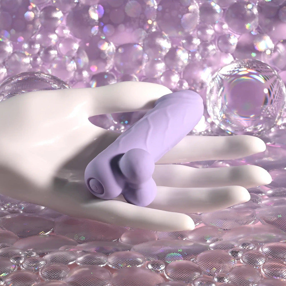 A purple silicone vibrator rests on a white hand against a backdrop of purple bubbles.