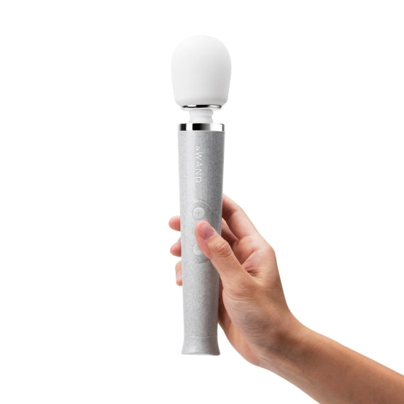 A hand holds a grey speckled wand massager with a white bulbous head.