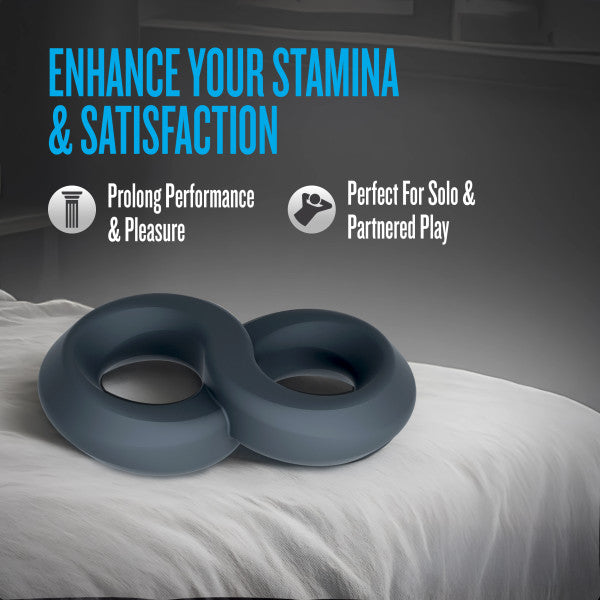 A grey double strap silicone cock ring on a white surface.