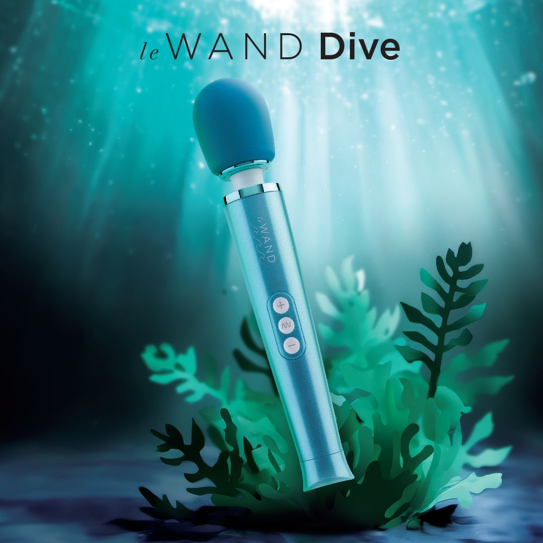 A blue waterproof wand massager with buttons is submerged in green seaweed.