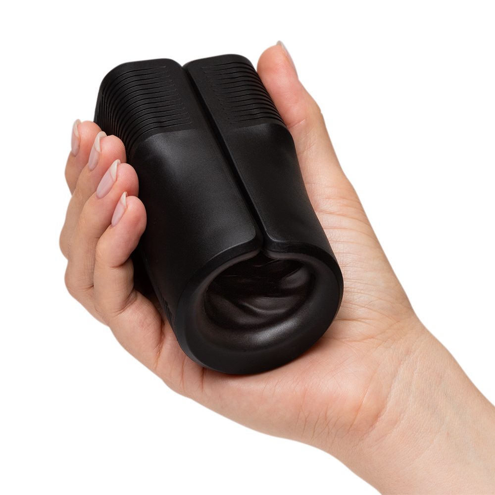 Black silicone vibrating open sleeve masturbator held in a hand.