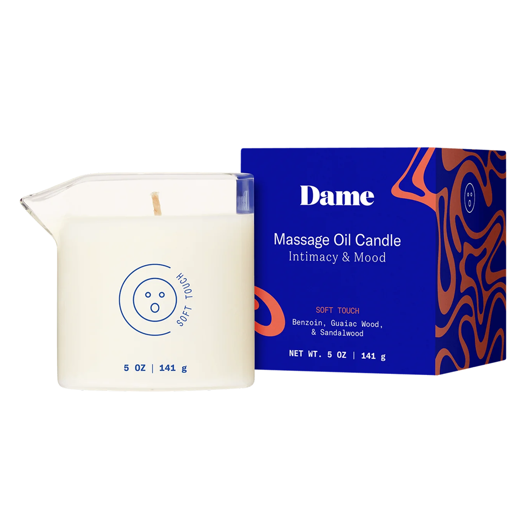 Dame Soft Touch Massage Oil Candle in a glass jar with a blue box.