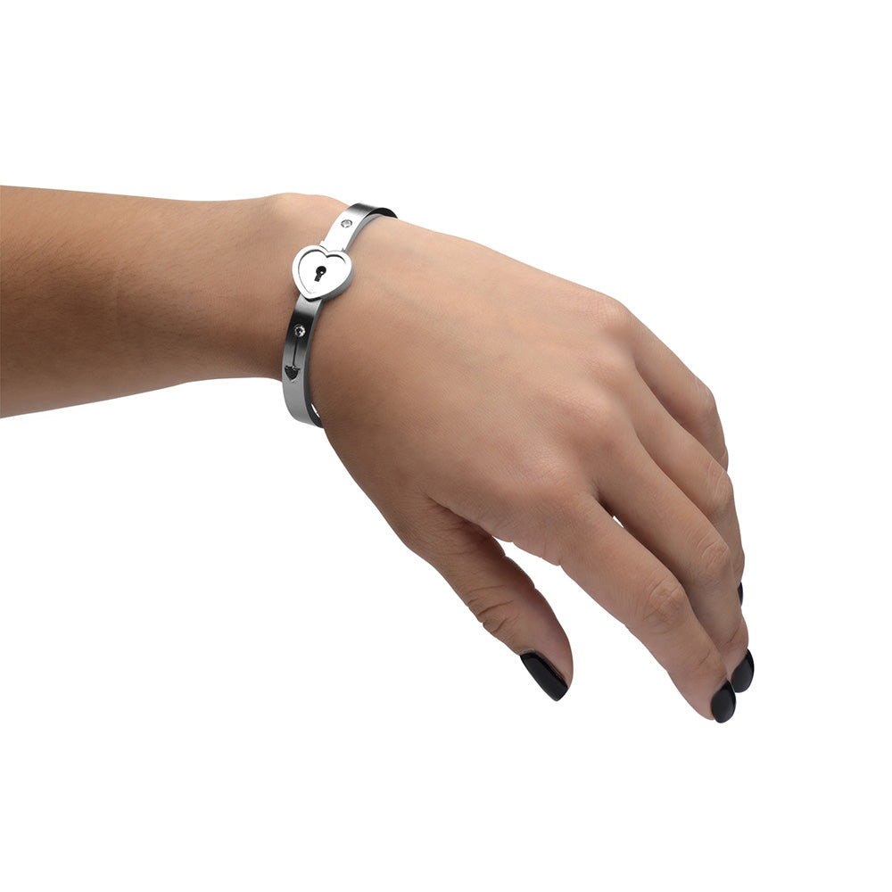 Silver heart lock bracelet on a wrist.