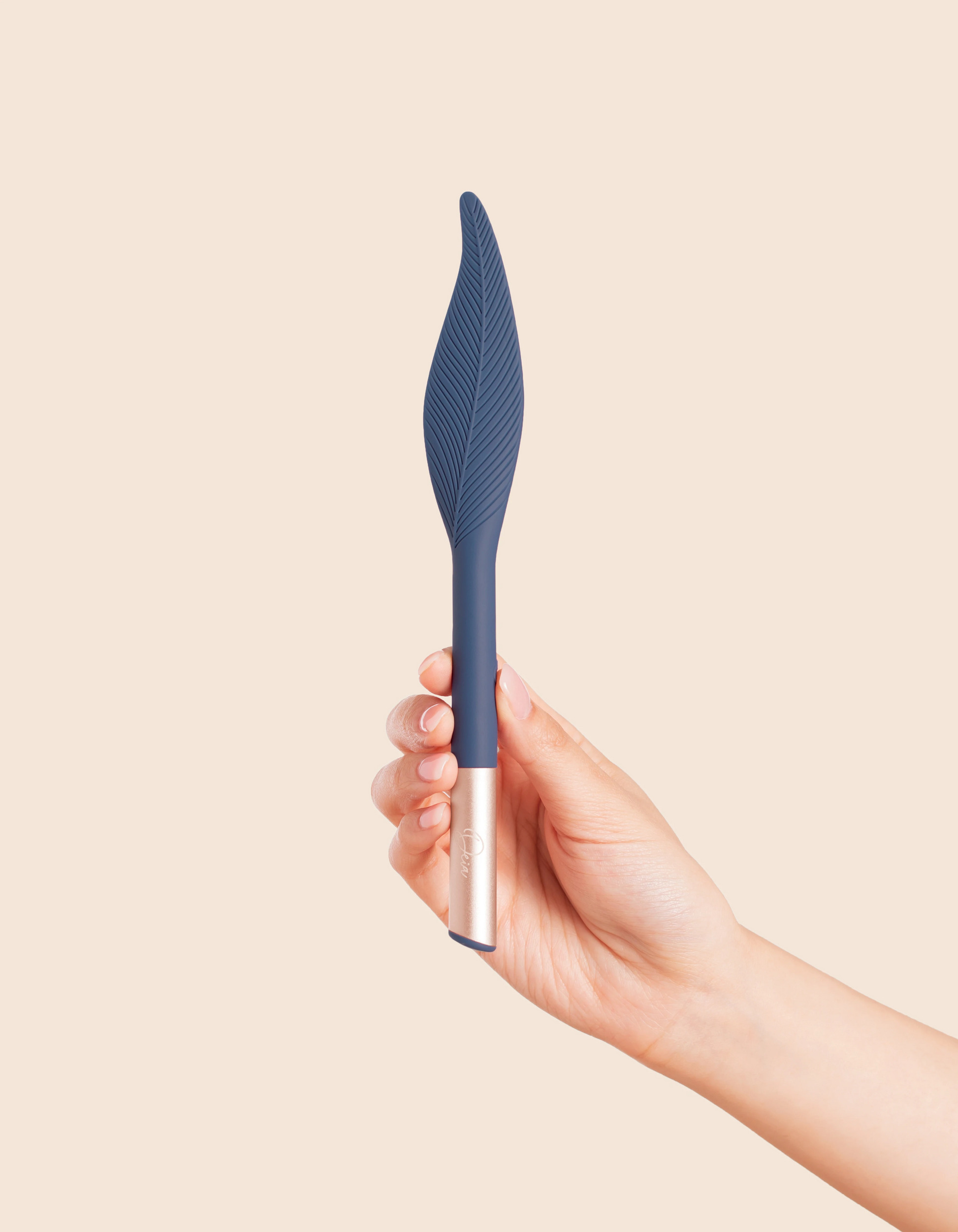 A hand holds a blue feather-shaped vibrator with a rose gold base.