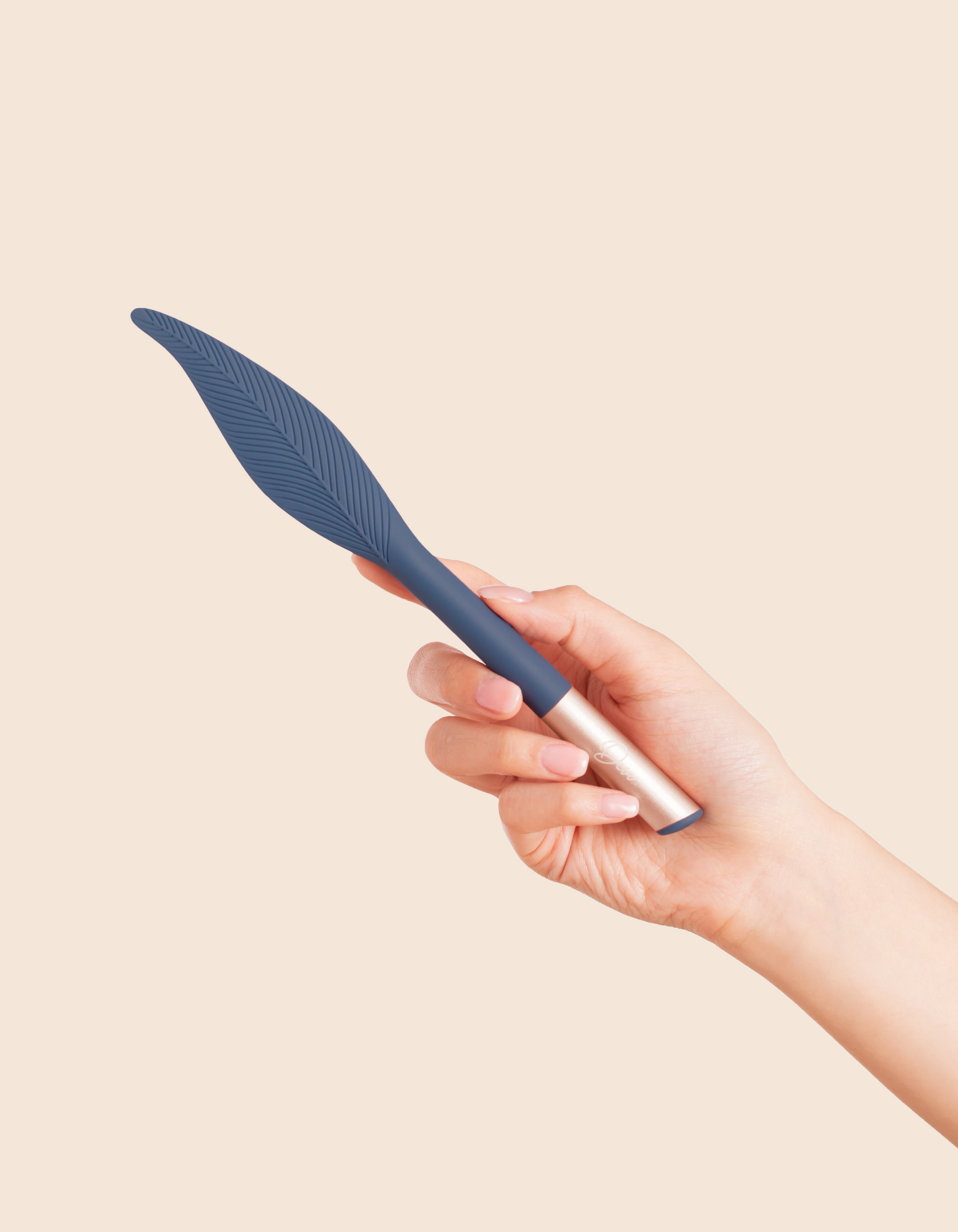 A hand holds a blue feather-shaped vibrator with a gold tip.