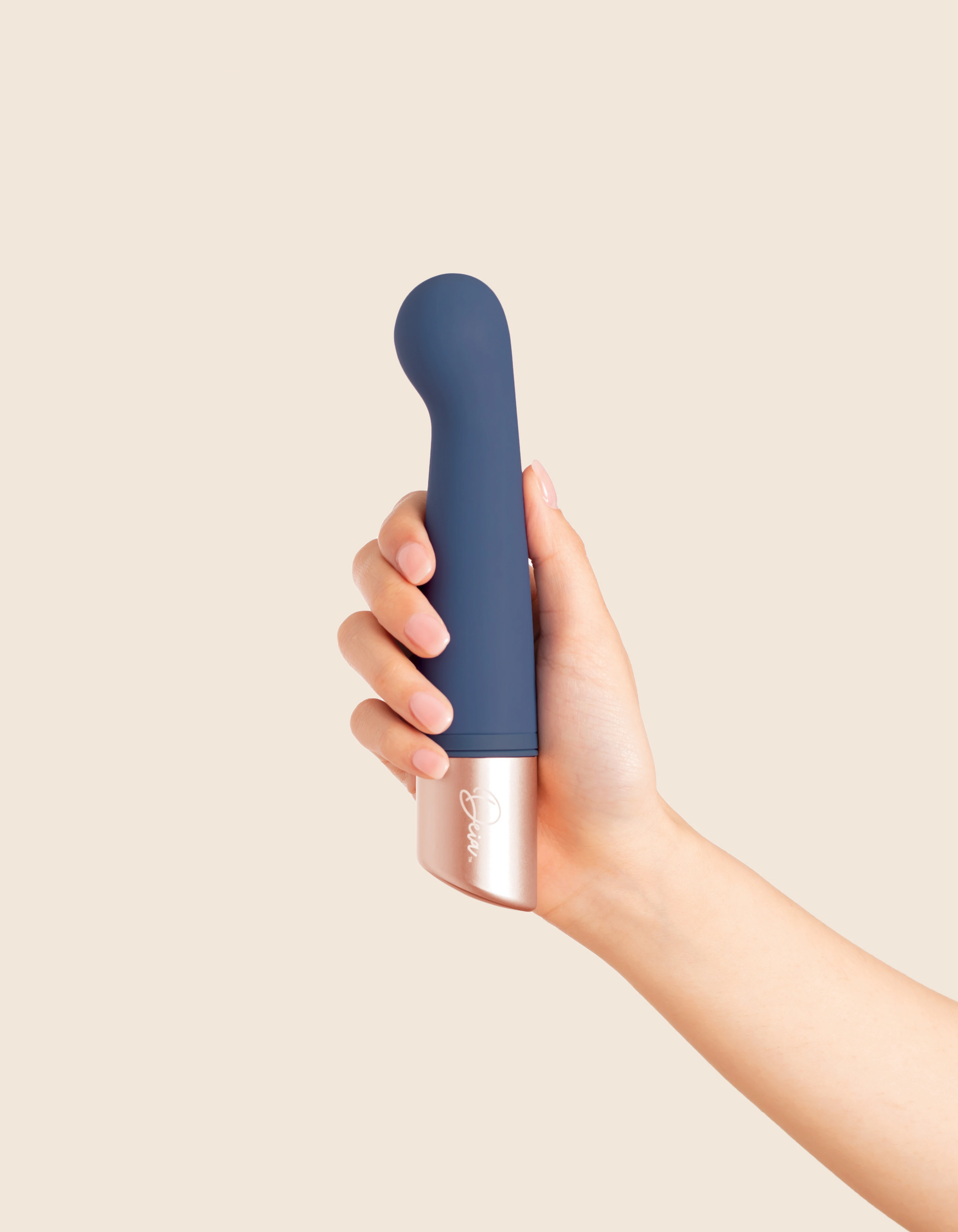 A hand holds a blue and rose gold dual motor vibrator.