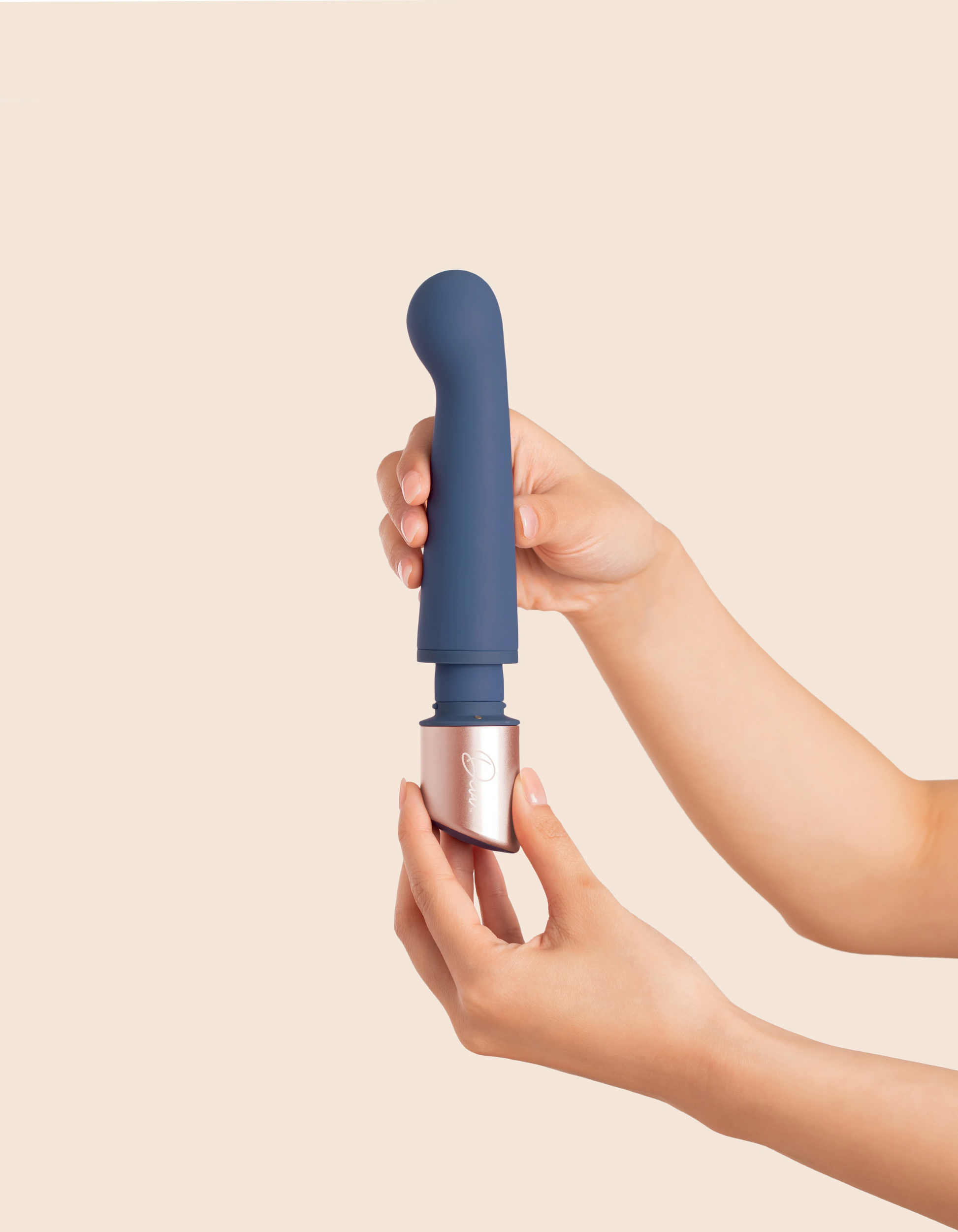 A blue silicone vibrator with a rose gold base is held by two hands.