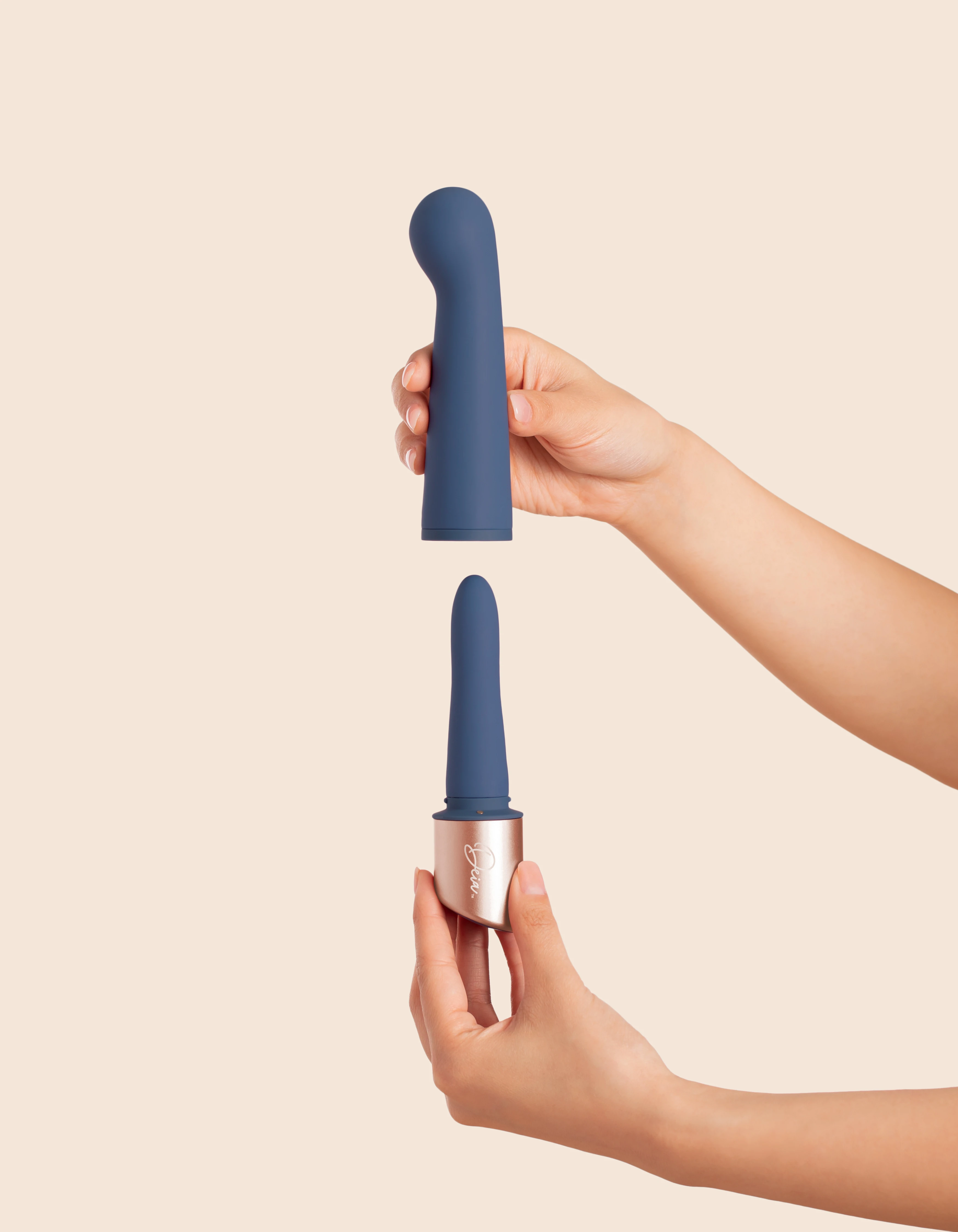 Blue silicone vibrator with rose gold base held by two hands.